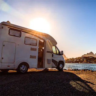 RV parked with mountains and sunset in the background, symbolizing Lemon Law rights for RVs and travel trailers in California.