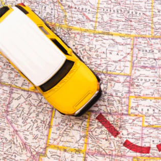 Toy car driving on a map, illustrating a route or travel journey